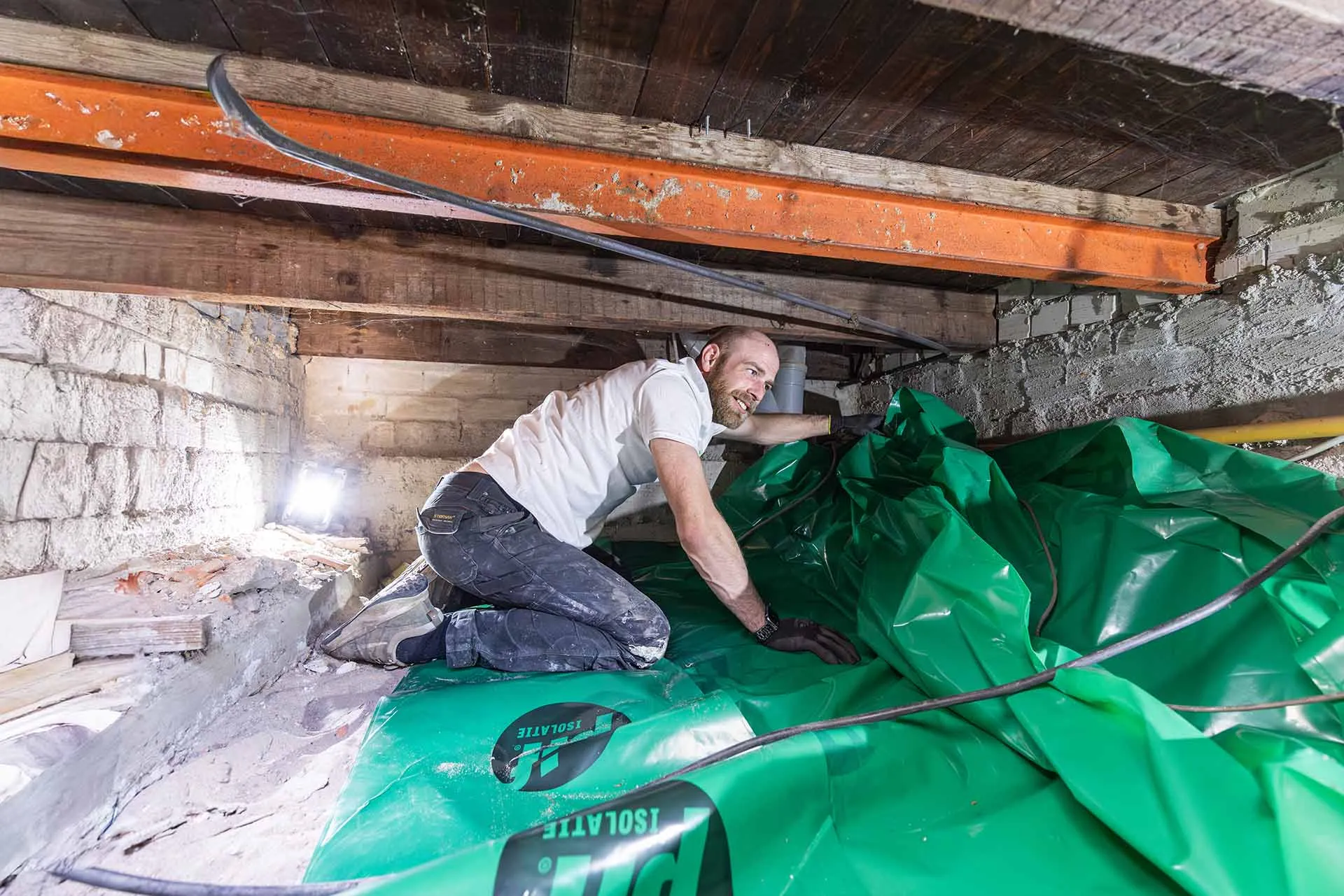 Monteur legt reflecterende bodemisolatie aan in een lage kruipruimte van een woning in Hoofddorp