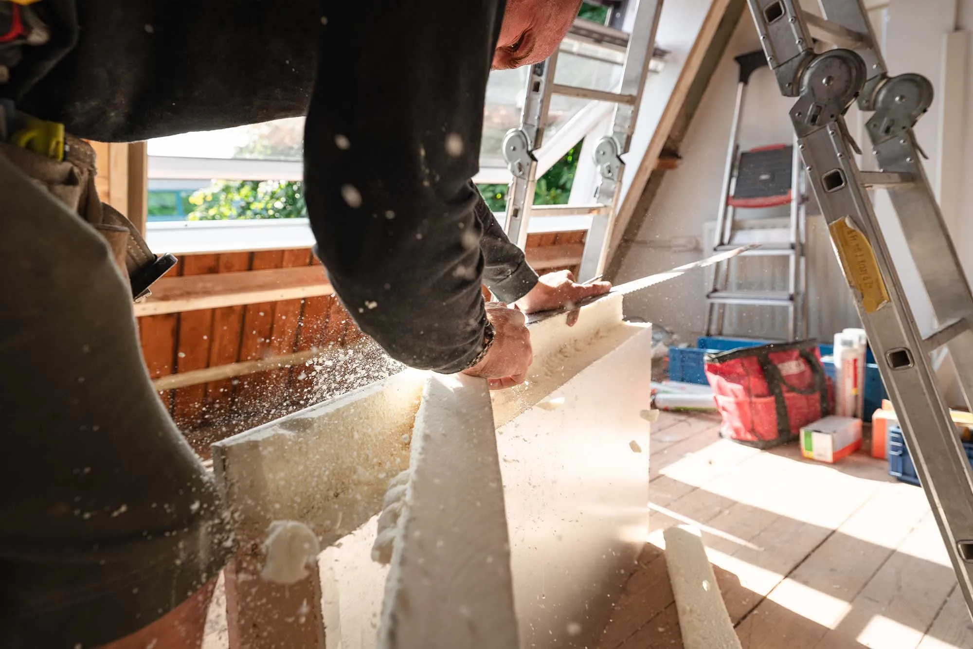 Monteur zaagt op zolder een isolatieplaat op maat voor dakisolatie van een woning in Hoofddorp