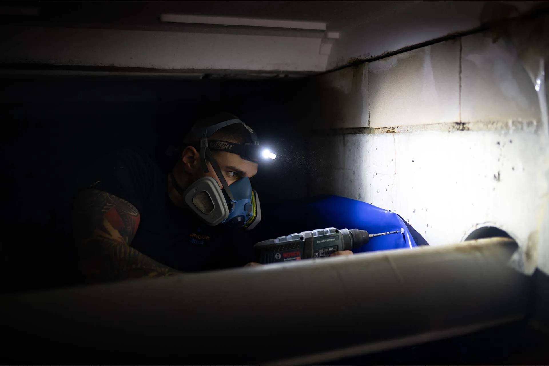 Fitter with a work light in a low crawl space under a home in Hoofddorp