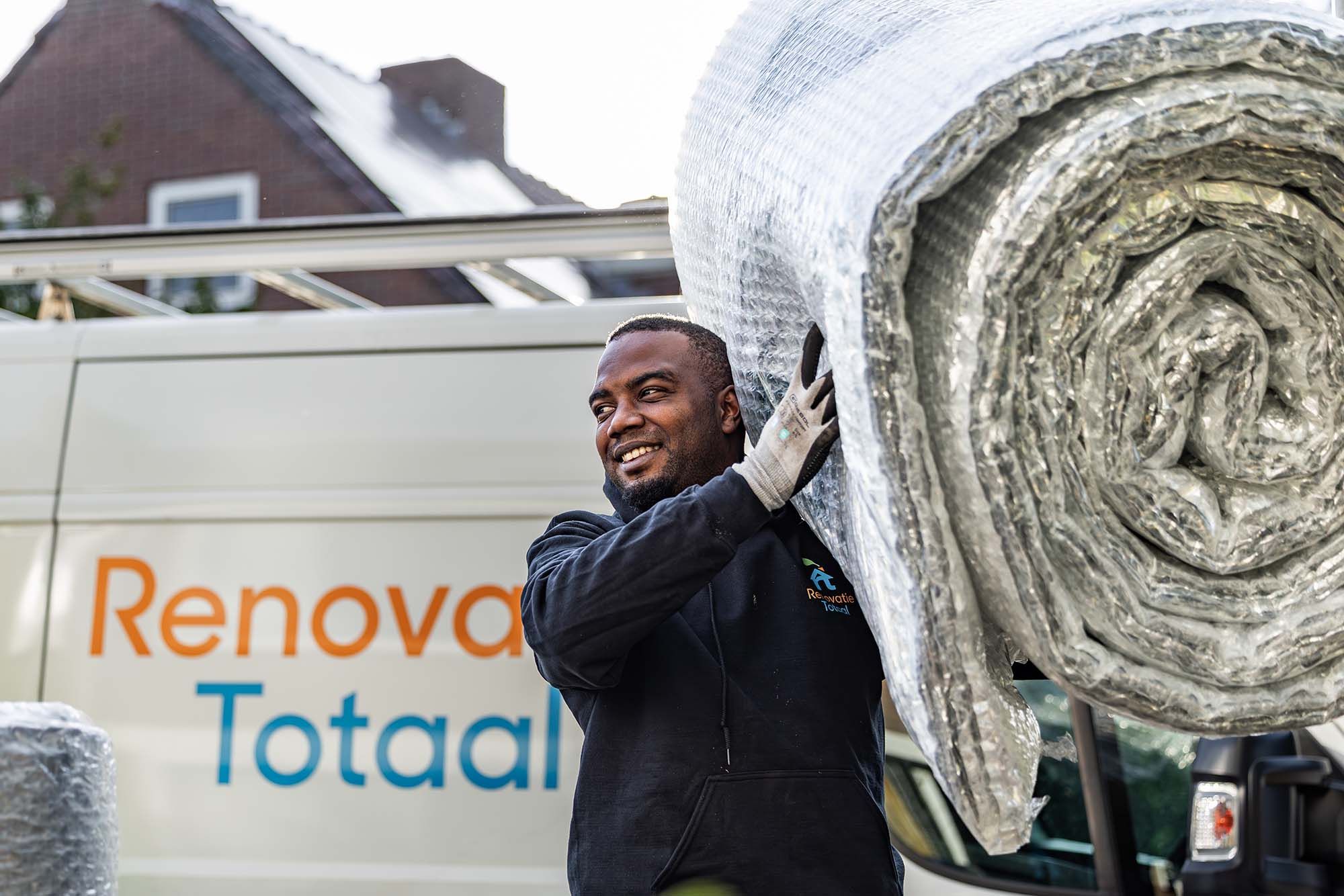 Monteur van Renovatie Totaal draagt een rol bodemisolatiemateriaal naar een woning in Hoofddorp