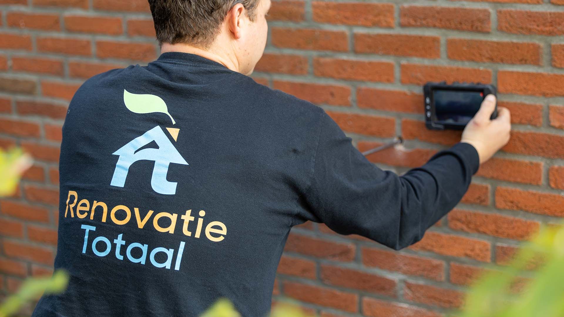 Adviseur onderzoekt de spouwmuur van een woning tijdens een inspectie in Hoofddorp